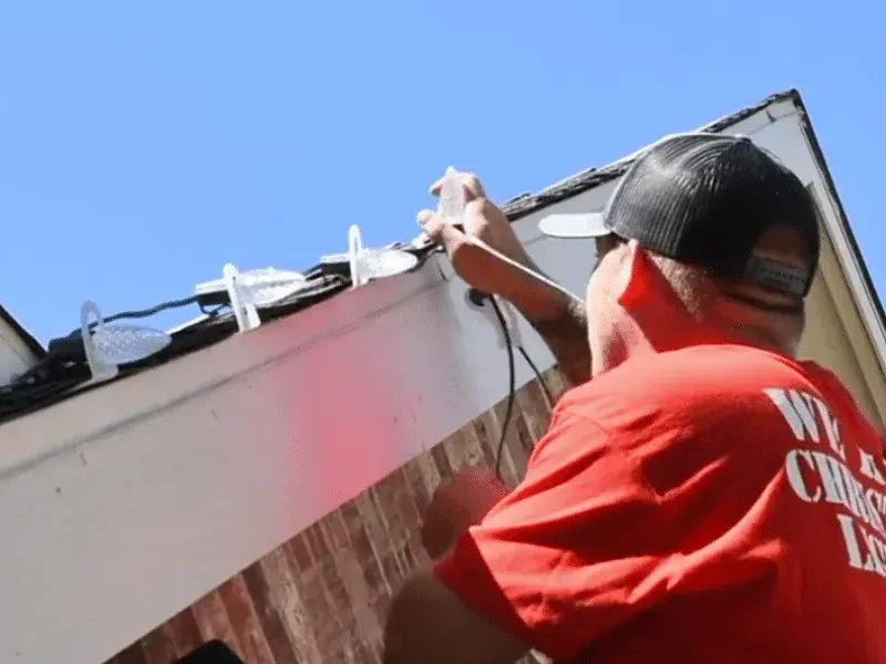 We Hang Christmas Lights installer clipping C9 Christmas lights to a roofline