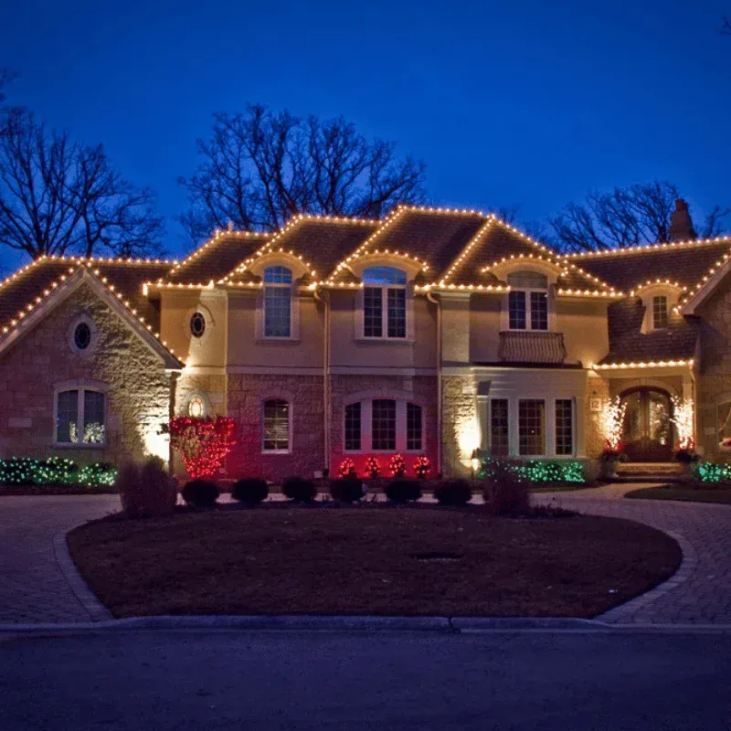 Large home outlined with classic C9 roofline Christmas lights at dusk